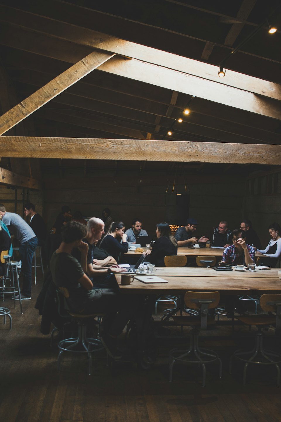 A group of colleagues working and talking at a wooden table.