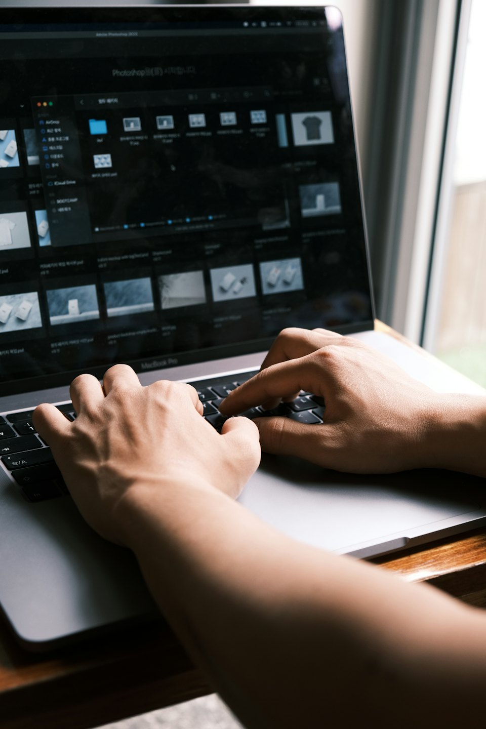 Hands typing on a laptop with design mockups on screen.